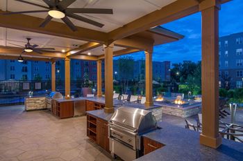 a covered patio with a grill and a spa at night